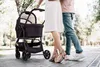 A couple walking with a baby stroller in a park. Produktbild-Vorschau