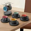 Espresso cups and saucers arranged on a wooden table, with a cup holder in the background. Produktbild-Vorschau