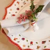A close-up of a Christmas-themed plate setting with a folded napkin, a snowman napkin ring, and holly with berries. Produktbild-Vorschau
