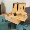 A wooden storage box with a combination lock, open to reveal various accessories and containers, placed on top of other decorative boxes. Produktbild-Vorschau