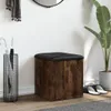 A storage ottoman with a wooden finish and black upholstered top is placed in an entryway next to an umbrella stand and a large potted plant. Podgląd zdjęcia produktu