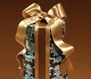 A close-up view of a gift-wrapped item with a large golden bow. Náhled obrázku produktu