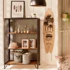A shelf unit with decorative items, including a surfboard, picture frames, and storage bins, in a room with a wooden wall. Náhled obrázku produktu