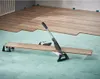 A vinyl and laminate cutter is shown on a light green underlayment, with wood flooring being installed in the background. Produktbild-Vorschau