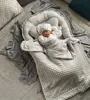 A newborn baby sleeping in a gray babynest with a matching blanket and hat. Produktbild-Vorschau
