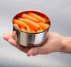 A hand holding a metal container filled with carrots. Produktbild-Vorschau