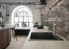 A modern kitchen with an industrial design, featuring a sink, faucet, brick wall, and a large arched window. Podgląd zdjęcia produktu