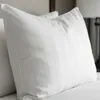A close-up view of a white pillow with vertical stripes, placed on a bed. Produktbild-Vorschau