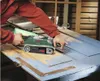 A person is using a Bosch belt sander to remove paint from a wooden door. Podgląd zdjęcia produktu