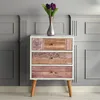 A chest of drawers with decorative drawer fronts and a vase of purple tulips on top, set against a paneled gray wall. Produktbild-Vorschau