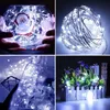A collage of four images showcasing white LED string lights used for decoration in various settings, including a glass vase with a Santa figurine, a tangled ball of lights, a glass bottle, and a miniature garden fence. Voir les images du produit