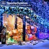 A nativity scene with figures and animals, decorated with blue and white string lights, set in a snowy environment. Produktbild-Vorschau