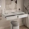 A modern white vanity table with open drawers, a bust sculpture, and a makeup brush holder, next to a grey upholstered stool and draped curtains. Produktbild-Vorschau