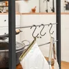 A close-up view of a kitchen shelf with pots and kitchen utensils hanging from hooks. Produktbild-Vorschau