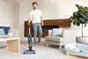 A man is vacuuming a living room with a Shark Hydrovac. Podgląd zdjęcia produktu