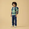A young boy stands facing sideways, wearing a backpack and a striped t-shirt. Produktbild-Vorschau