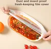 A person is covering a plate of food with a plastic wrap. Produktbild-Vorschau