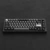 A black mechanical keyboard with silver and gray keycaps is shown from a slightly elevated front-facing angle on a dark textured surface. Produktbild-Vorschau