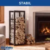 A metal firewood rack filled with logs is placed next to a fireplace with a fire burning. A sofa is visible on the left. Náhľad obrázku produktu