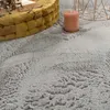 A close-up view of a fluffy gray rug with a yellow basket and a pink candle in the background. Voir les images du produit
