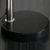 A close-up view of the base of a floor lamp, showing the black marble base and the silver pole. Produktbild-Vorschau