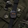 A watch is placed on a green fabric background with zippers and buttons. Náhľad obrázku produktu