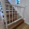 A white baby gate is installed at the bottom of a wooden staircase. Voir les images du produit