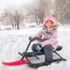 A young girl is riding a sled in a snowy park. Produktbild-Vorschau
