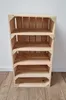 A wooden crate shelf unit with four shelves, standing on a wooden floor against a white wall. Produktbild-Vorschau