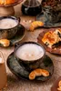 A close-up shot of coffee cups with frothy coffee and small pastries, set on a textured surface. Podgląd zdjęcia produktu