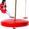 A young girl is sitting on a red disc swing, with another red disc swing in the background. Náhled obrázku produktu