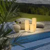 Three LED candles are placed on a wooden deck next to a swimming pool, with a lush green landscape in the background. Podgląd zdjęcia produktu