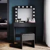 A modern black vanity table with LED lights and a mirror, placed in a bedroom setting with a stool in front. Anteprima dell’immagine prodotto