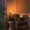 A cozy living room scene with a chair, side table, and a lamp with two candle-shaped bulbs. Produktbild-Vorschau