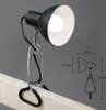 A black desk lamp with a clamp attached to a wooden surface, with a technical drawing of the lamp showing dimensions. Produktbild-Vorschau
