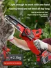 A person is holding a red and black mini chainsaw and cutting a tree branch. Produktbild-Vorschau