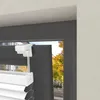 Close-up of a white pleated blind attached to a dark gray window frame, with a blurred background of autumn trees. Produktbild-Vorschau