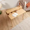 A wooden desk with a notebook and pencils, placed in a living room setting next to a sofa. Produktbild-Vorschau