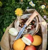 A pocket knife is placed on a bag of nuts and fruits, surrounded by grass and flowers. Náhled obrázku produktu