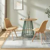 Two yellow upholstered chairs are placed around a round wooden table with a green base in a room with natural light. Náhled obrázku produktu