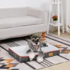 A dog is lying on a dog bed in front of a sofa, on a rug. Náhled obrázku produktu
