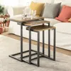 A set of nesting tables with wooden tops and dark metal frames are placed on a rug in front of a sofa with colorful cushions. Voir les images du produit
