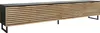 A long, low TV stand with a black top and black legs, featuring a slatted wood-grain front with four doors. Náhled obrázku produktu