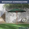 A green umbrella is set up on a wooden deck next to a stone wall and a chair, with grass in the foreground. Produktbild-Vorschau