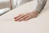 A hand is gently pressing down on a soft, mint-colored surface, likely a bedsheet or mattress topper. Produktbild-Vorschau