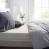 A close-up view of a bed with cream-colored sheets and gray pillows and duvet. Anteprima dell’immagine prodotto
