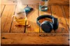A pair of black Philips headphones rests on a wooden table next to a glass of tea and a smartphone. Voir les images du produit