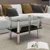 A glass coffee table with a black shelf is placed on a white rug in front of a white sofa with several pillows. Náhľad obrázku produktu