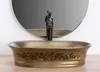 A close-up shot of a bronze vessel sink with ornate detailing, a black faucet with a decorative top, and a circular mirror in the background. Náhľad obrázku produktu