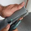 A hand is cutting a piece of gray foam insulation with a utility knife. The insulation has the text "SCORPROTECT" printed on it. Produktbild-Vorschau